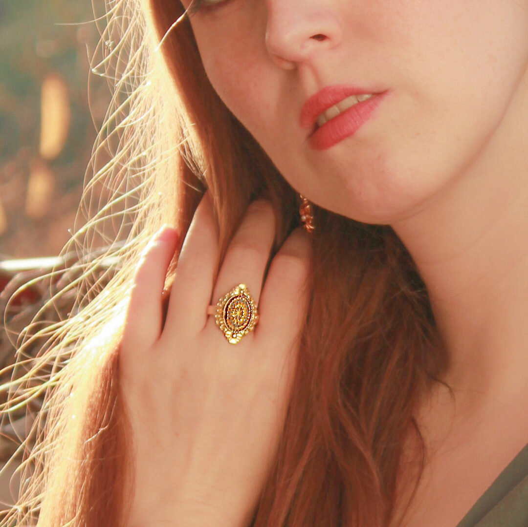A-quiet-redhead-girl-softly-touching-her-long-mane-and-wearing-and-adjustable-gold-plated -vintage-ring