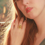 A-quiet-redhead-girl-softly-touching-her-long-mane-and-wearing-and-adjustable-gold-plated -vintage-ring
