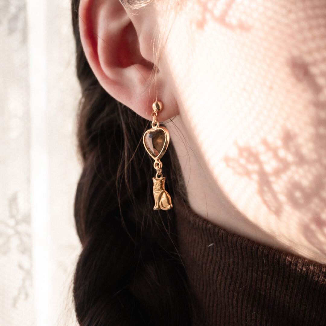 Close-up-of-a-girl-wearing-dangling earring-shaped-like-a heart-and-cat.